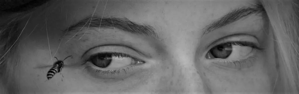 Black and white close-up of a woman's face with a bee crawling near her eye