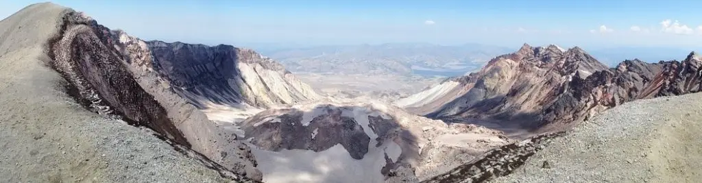 Panoramic view of Mount St. Helens crater with surrounding volcanic peaks and expansive valley below